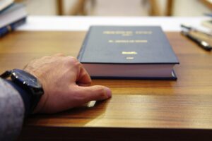 Hand resting on a wooden desk near a thick book titled 'Criminal Code'.